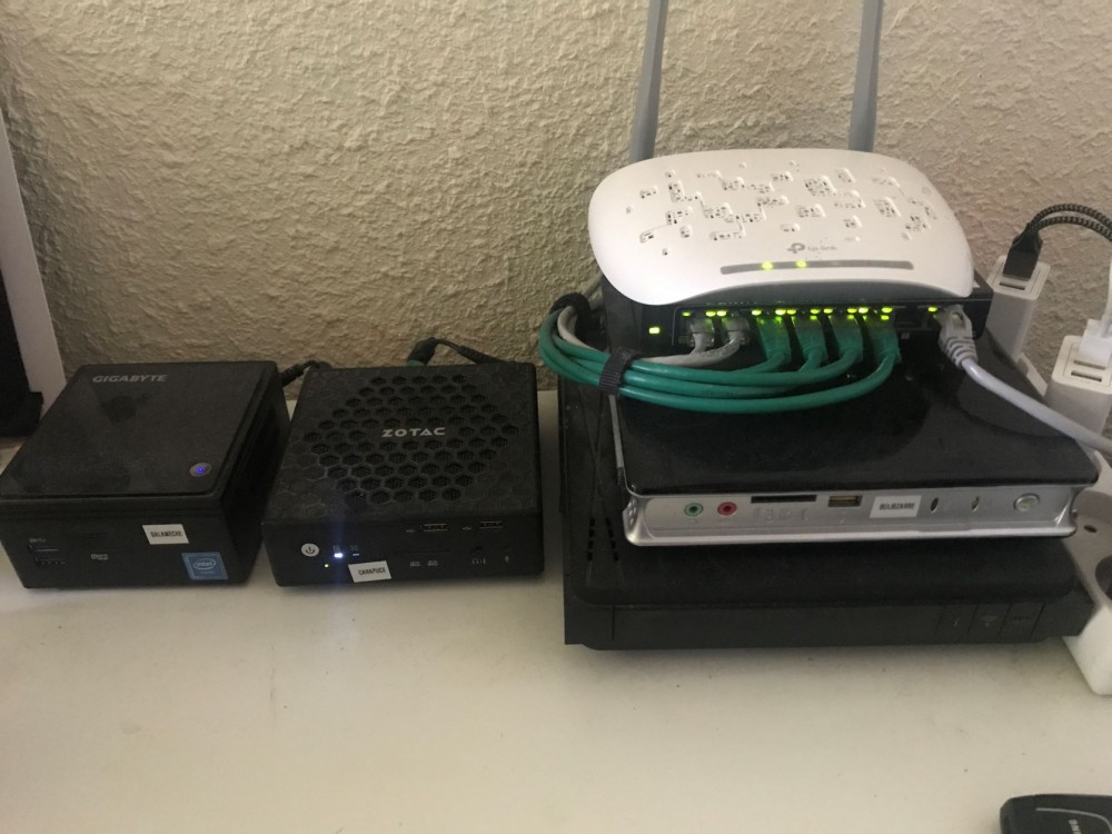 Une photo de mon cluster de mini-machines, avec une Livebox noire, un switch et une borne Wifi.